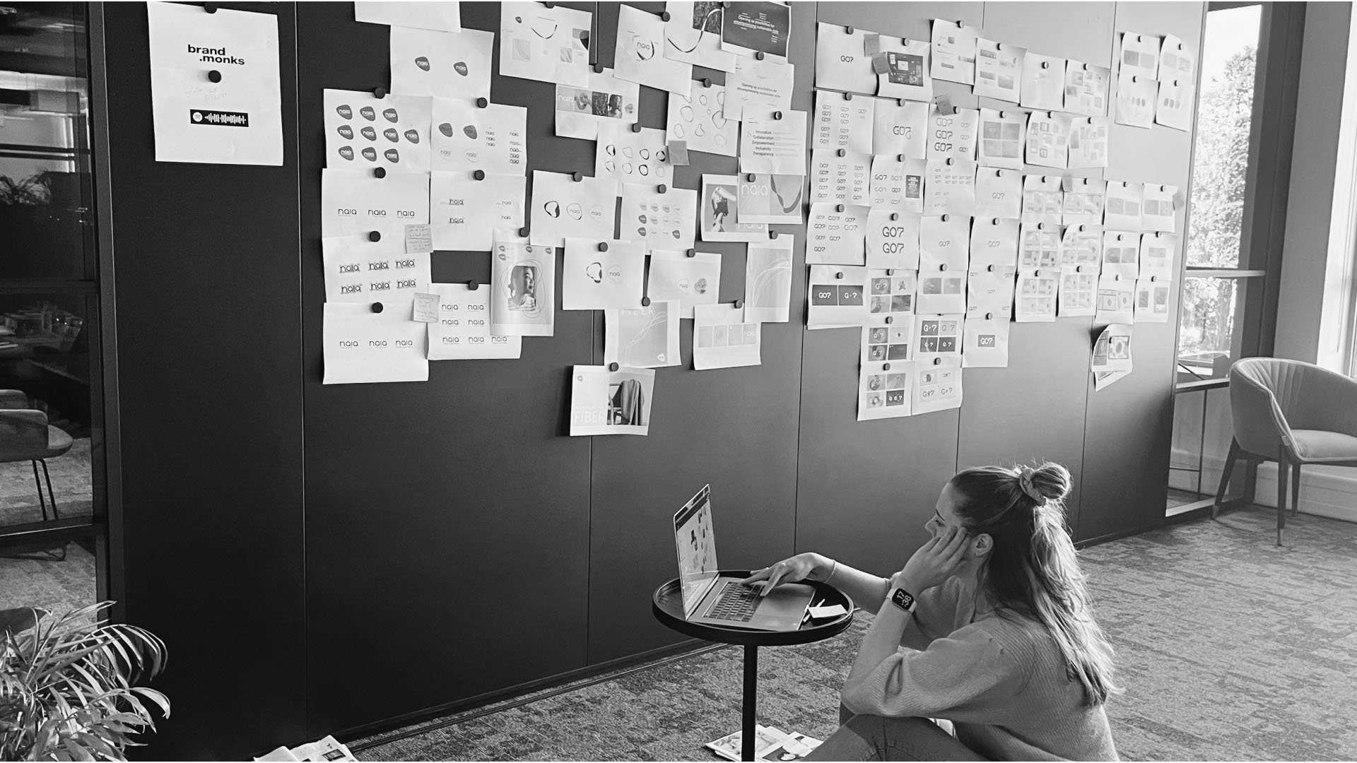 A wall full of artistic concepts and a person working on their laptop